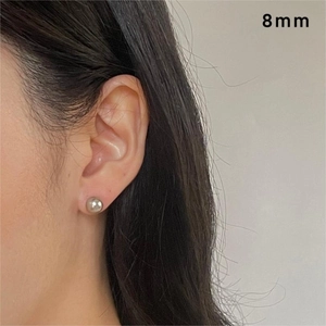 Close-up of 8mm silver sphere stud earrings showing minimalist style and metallic luster