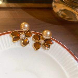 Close-up of 18k gold floral earrings with brown enamel, pearl center, and small zircon