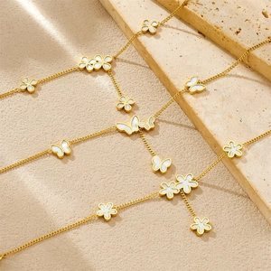 Gold stainless steel bracelet with white shell flower and butterfly pendants on sand