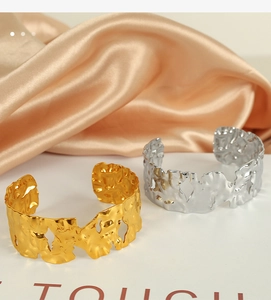 Detail of wide open bangles with irregular hammered texture in gold and silver finish