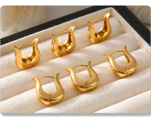 Dettaglio di tre paia di orecchini a U placcati in oro 18K su velluto bianco liscio