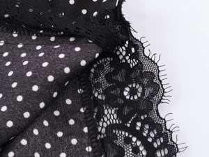 Detail of delicate black eyelash lace trim and white polka dot fabric on the hem