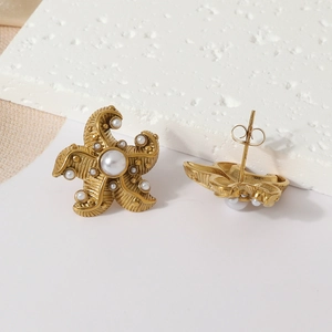 Ocean style gold starfish earrings with pearls on textured white stone background