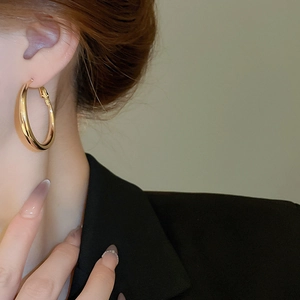 Close-up of chunky gold teardrop hoop earrings with high-polish finish on model