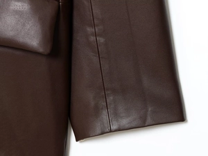 Detailed close-up of stitching and texture on a dark brown leather blazer jacket