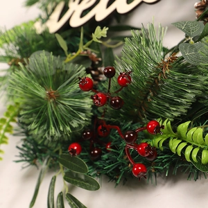 Christmas wreath with olive branches, pine needles, berries and a wooden Welcome sign