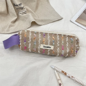 Detailed view of floral tweed pencil case with purple handle and soft aesthetic props