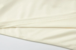 Detailed macro view of the cream-colored knitted fabric texture and quality edge stitching