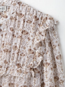 Détail du chemisier en mousseline florale avec col montant à volants et motif beige