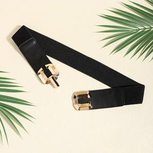 Close-up of black elastic waist belt with gold geometric buckle and leather trim