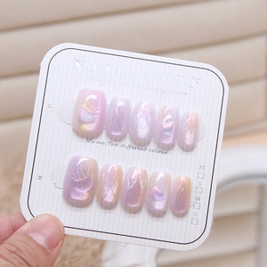 Short square lavender cat-eye press-on nails set with abstract line designs on display card