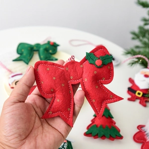 Red felt Christmas bow ornament with gold dots and green leaf accents for festive decor