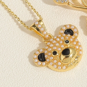 Détail macro d'un collier doré 14K avec pendentif ours en perles et émail noir fin