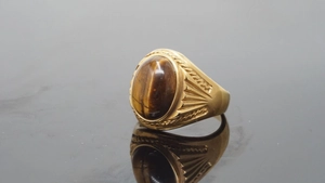Macro detail of gold-plated vintage ring featuring a polished oval tiger eye stone inlay