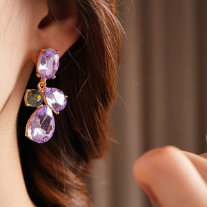 Close-up of vintage gold earrings with purple and green teardrop-shaped crystals