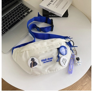 Macro shot of white nylon waist bag with blue strap and astronaut keychain accessory