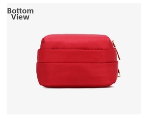 Detail view of the red nylon crossbody bag showing the bottom and side with gold zipper