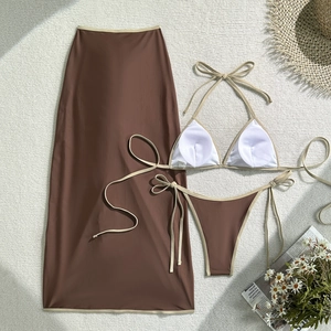 Detailed flat lay of a brown three-piece bikini set with contrast trim and long beach skirt