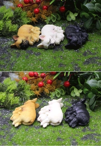Detailansicht von drei schlafenden französischen Bulldoggen-Figuren in einer Gartenumgebung