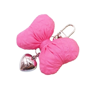 Pink fabric bow keychain with silver heart pendant on white background for bag charm