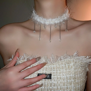 Close-up of white plush choker with crystal fringe tassels and delicate silver bead details