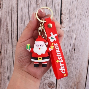Detail of Santa Claus PVC keychain with red wristband and gold metal clip held in hand