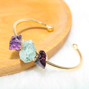 Close-up of a gold-plated adjustable bracelet featuring three raw natural crystal stones