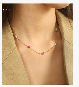 Close-up of titanium steel gold chain with five colorful enamel square pendants on neck