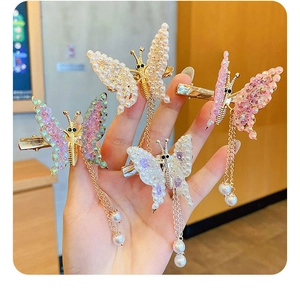 Detailed macro view of butterfly hair clips with elegant long gold tassel and pearls