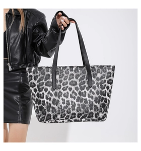 Borsa tote chic con stampa leopardata e manici in pelle nera tenuta da una modella