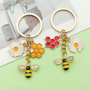 Detailed view of bee keychains with hexagonal enamel honeycomb and daisy charms