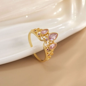 Detailed close-up of golden crown ring featuring pink pear stones and red accents