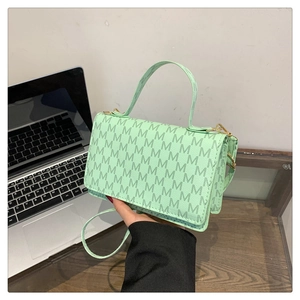 Detail of mint green PU leather bag with M-pattern print and golden hardware accents