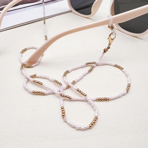 Detail of pink seed beads and gold accents on a stylish glasses chain strap