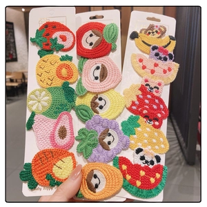 Detail of embroidered fruit and animal hair clips including strawberry and panda motifs