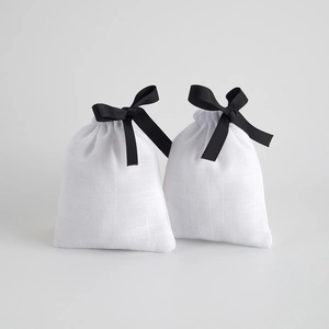 White cotton drawstring pouch with black ribbon bow for jewelry and gift storage