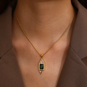Collier en or élégant avec pendentif en forme de losange vert émeraude porté par un modèle