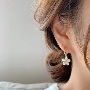 Elegant gold hoop earrings with white cat-eye stone flower petals worn by a model