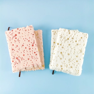 Close-up of pink and white plush star notebooks with gold foil moons on blue background