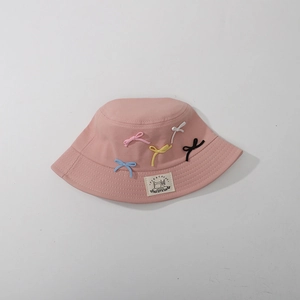 Close-up of pink children bucket hat featuring colorful bow ties and fabric brand label