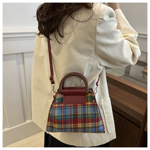 Detail of British style plaid shoulder bag with red leather trim and brown handle