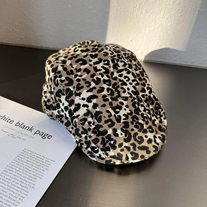 Detailed side view of vintage leopard print ivy cap on a dark background next to a magazine