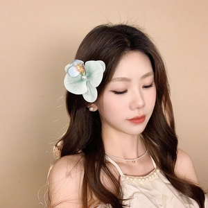 Detail showing elegant orchid hair clip with pearl center and matching pearl necklace