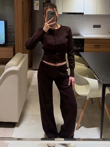 Detail of chocolate brown knit cardigan and wide-leg trousers set in a home interior setting