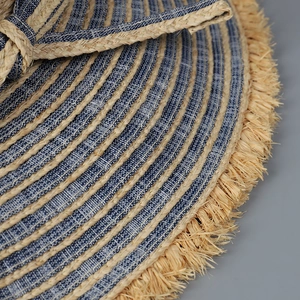 Macro detail of hand-woven raffia and denim wide brim sun hat with frayed edge design