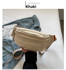 Close-up of khaki canvas chest bag featuring white letter embroidery and adjustable strap