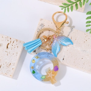 Detail of resin letter Q keychain with blue tassel and ocean beach starfish elements