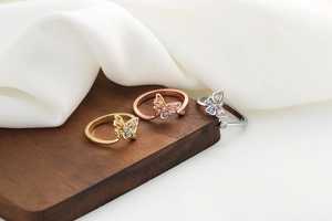 Three hollow butterfly rings in gold, silver, and rose gold with colorful zircon stones