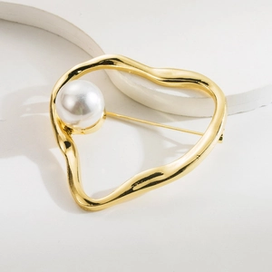 Minimalist golden metal heart brooch with round white pearl on elegant stone background