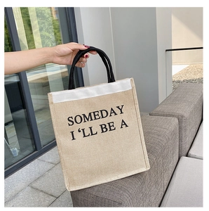 Detail of jute tote bag showing black handle and artistic typography on burlap fabric